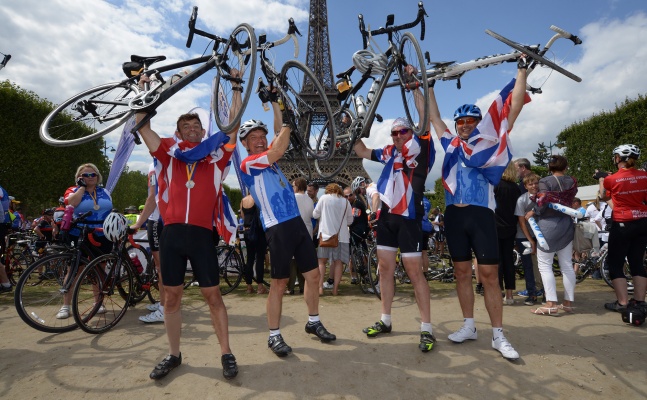 Cyclists lifting up their bikes in front of Eiffel tower at the end of London to Paris charity ride.