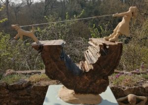 Wooden sculpture of dog pulling owner along