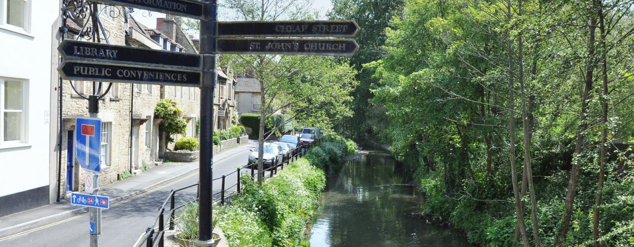 A signpost next to the river in Frome town centre, pointing to local streets and attractions