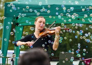 lady playing violin surrounded by bubbles