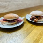 bacon roll and sausage roll on plates on a table