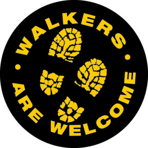 Walkers Are Welcome circular logo in black and gold, with golden boot prints in the centre