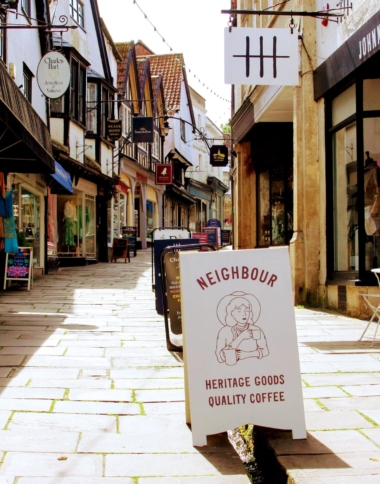 a view looking up Cheap Street in Frome, with Shop advertising boards straddling the leat.
