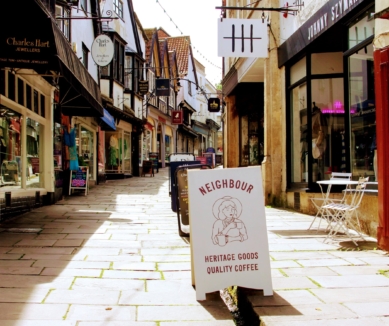 a view looking up Cheap Street in Frome, with Shop advertising boards straddling the leat.