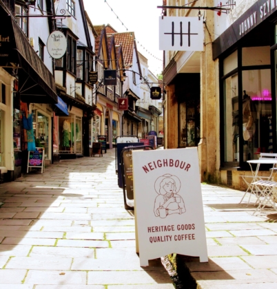 a view looking up Cheap Street in Frome, with Shop advertising boards straddling the leat.